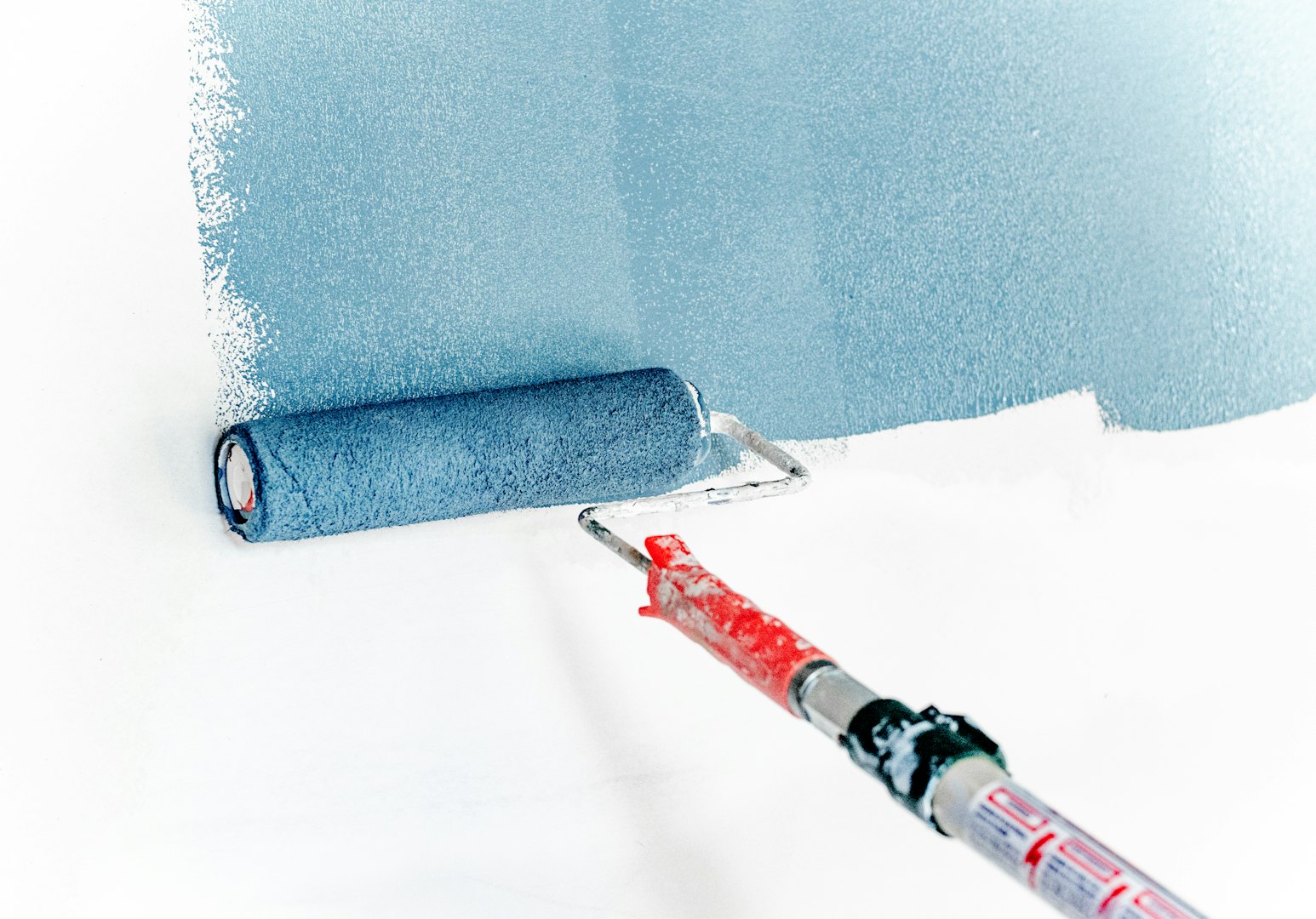A person wearing gray work attire is using a pressure washer to clean a stone surface in a garden area surrounded by neatly trimmed hedges.